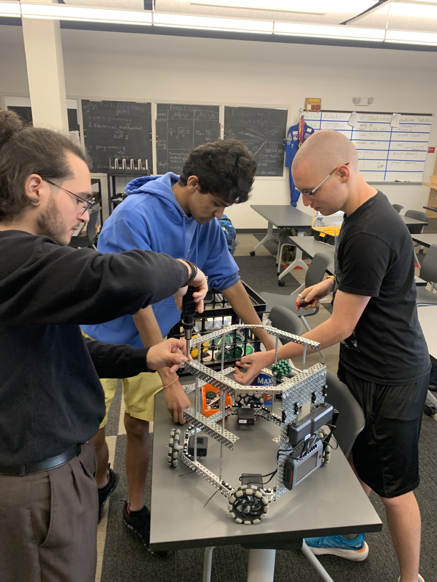 A group of men working on a robotDescription automatically generated